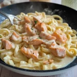 Creamy Salmon Alfredo pasta dish with herbs and garnishes
